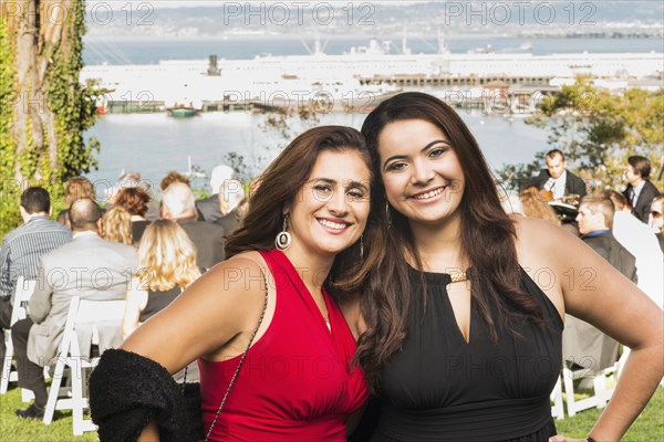 Hispanic mother and daughter smiling at wedding