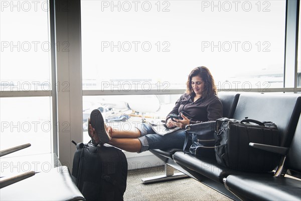 Hispanic woman texting on cell phone in airport