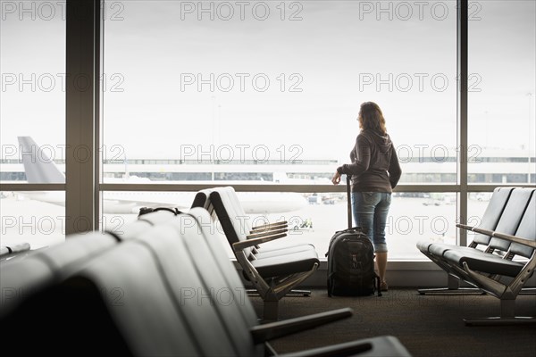 Hispanic woman looking out airport window