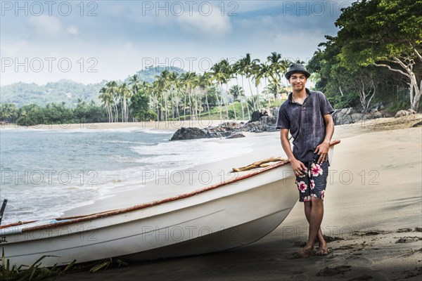 Hispanic man standing near boat on beach