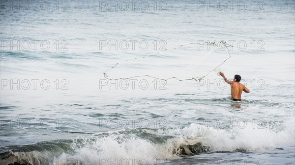 Man throwing fishing net into ocean waves