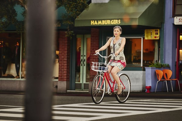 Older Caucasian woman riding bicycle in crosswalk