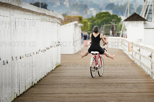 Older Caucasian woman riding bicycle on wooden dock