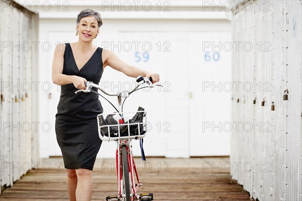 Older Caucasian woman walking bicycle on wooden dock
