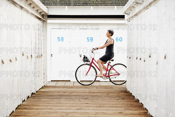 Older Caucasian woman riding bicycle on wooden dock