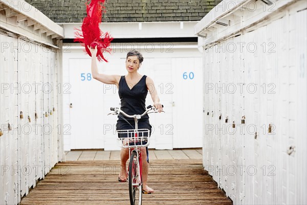 Older Caucasian woman riding bicycle on wooden dock