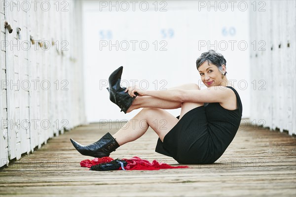 Older Caucasian woman taking off boots on wooden dock