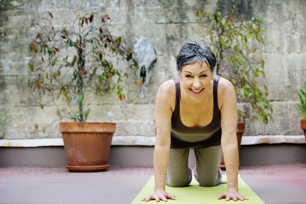 Older Caucasian woman practicing yoga in courtyard