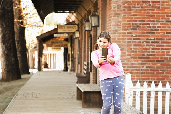 Mixed race girl taking selfie on sidewalk