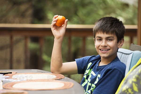 Mixed race boy eating fruit at table on porch