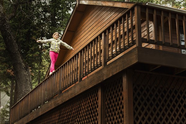 Mixed race girl balancing on balcony banister