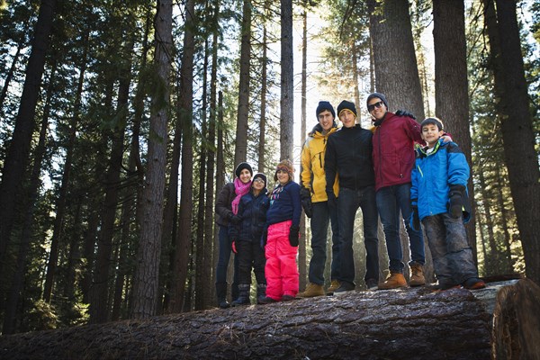 Family standing on log in remote forest