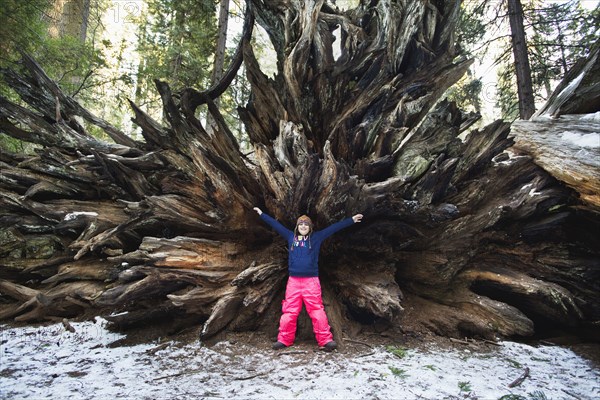 Mixed race girl standing under uprooted tree in forest