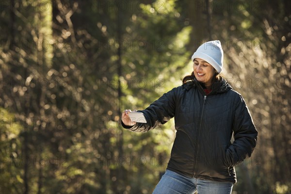 Hispanic woman taking selfie in forest