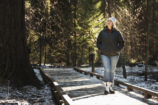 Hispanic woman on wooden walkway in snowy forest