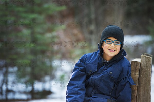 Hispanic boy sitting on chair in forest