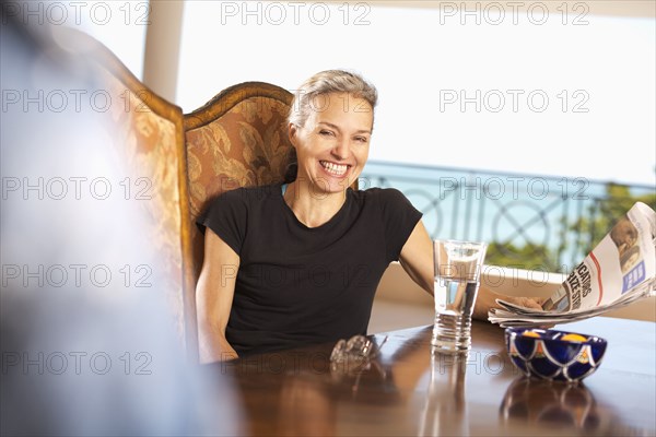 Hispanic woman reading newspaper at table