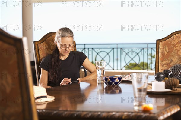 Hispanic woman using cell phone at table