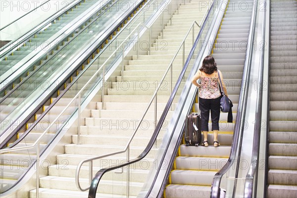 Hispanic woman standing on escalator