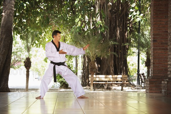 Hispanic man practicing martial arts on patio