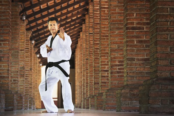 Hispanic man practicing martial arts in hallway