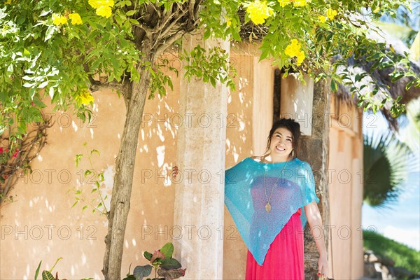 Hispanic woman smiling outside house