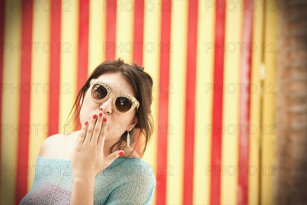 Hispanic woman in sunglasses blowing kisses