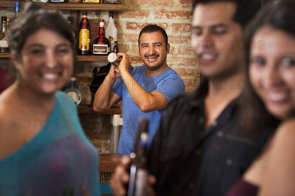 Hispanic bartender making drinks in bar