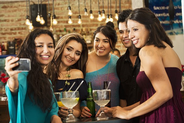 Hispanic friends taking selfie in bar