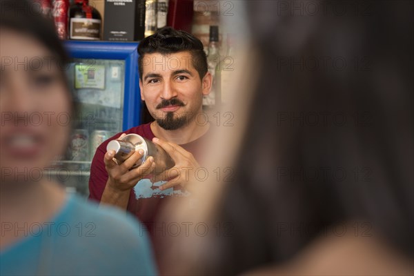 Hispanic bartender making drinks in bar