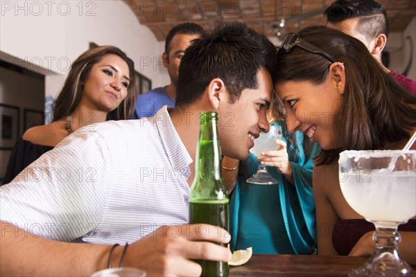 Hispanic couple touching foreheads in bar