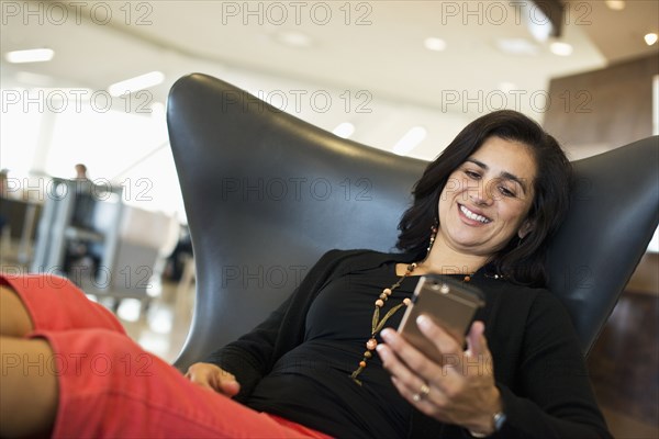 Hispanic businesswoman using cell phone in airport