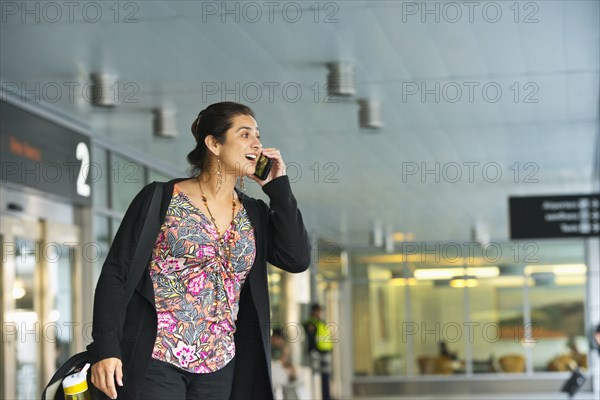 Hispanic businesswoman talking on cell phone in airport