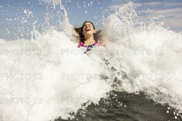 Mixed race girl playing in ocean waves