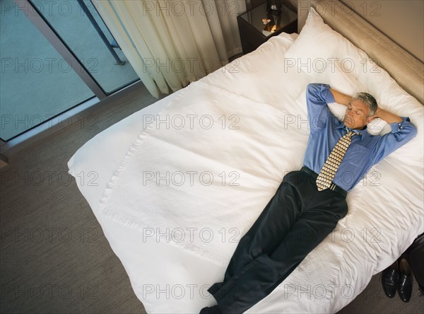 Caucasian businessman laying on hotel bed