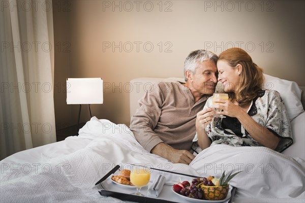 Smiling couple having breakfast in bed