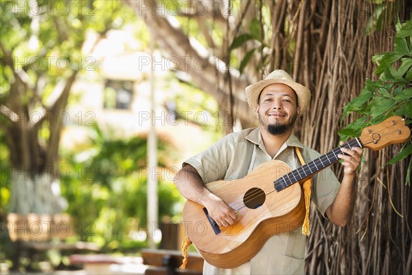 Hispanic musician playing guitar in park