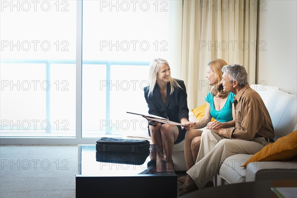 Businesswoman talking to couple on sofa