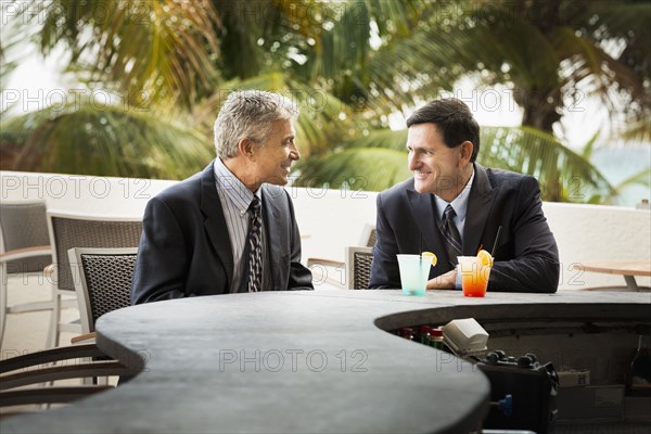 Caucasian businessmen with cocktails at patio bar