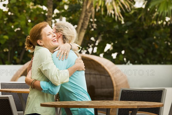 Caucasian women hugging on restaurant patio