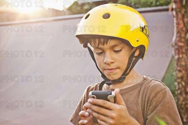 Mixed race boy in helmet using cell phone