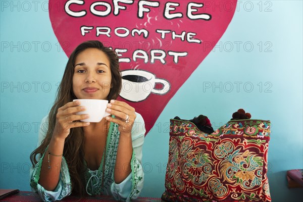 Hispanic woman drinking coffee in cafe