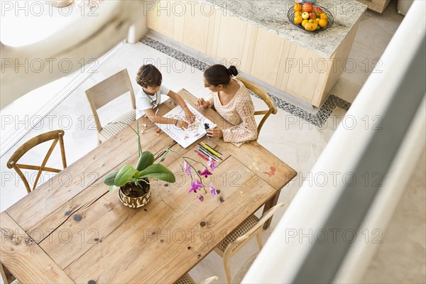 Hispanic mother and son playing game at table