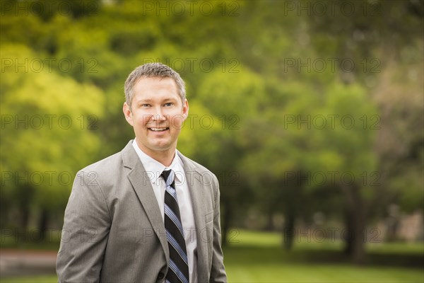 Caucasian businessman smiling in park