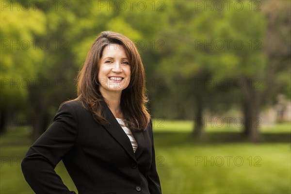 Hispanic businesswoman smiling in park