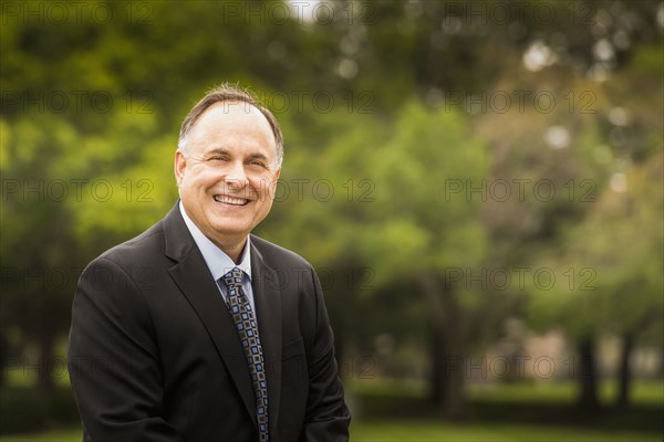 Caucasian businessman smiling in park