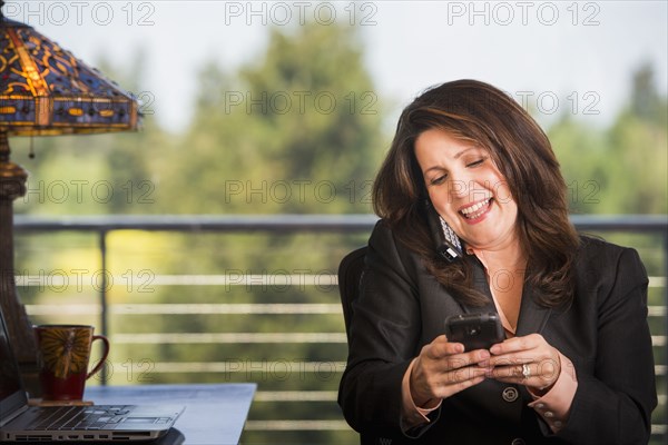 Hispanic businesswoman using cell phone in office