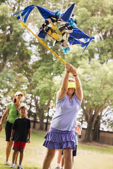 Blindfolded girl hitting pinata at party