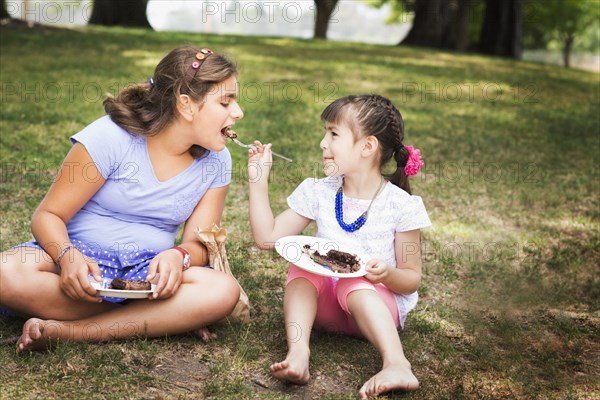 Girl feeding sister cake at birthday party in park