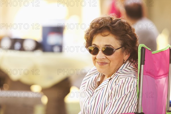 Smiling older woman sitting in camping chair